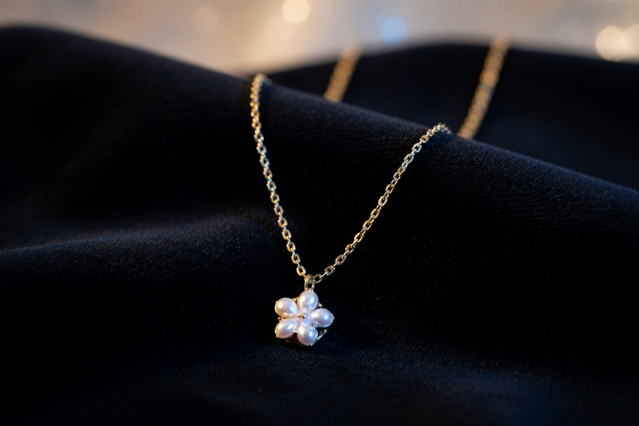 Gold necklace with a flower-shaped pendant on a dark background